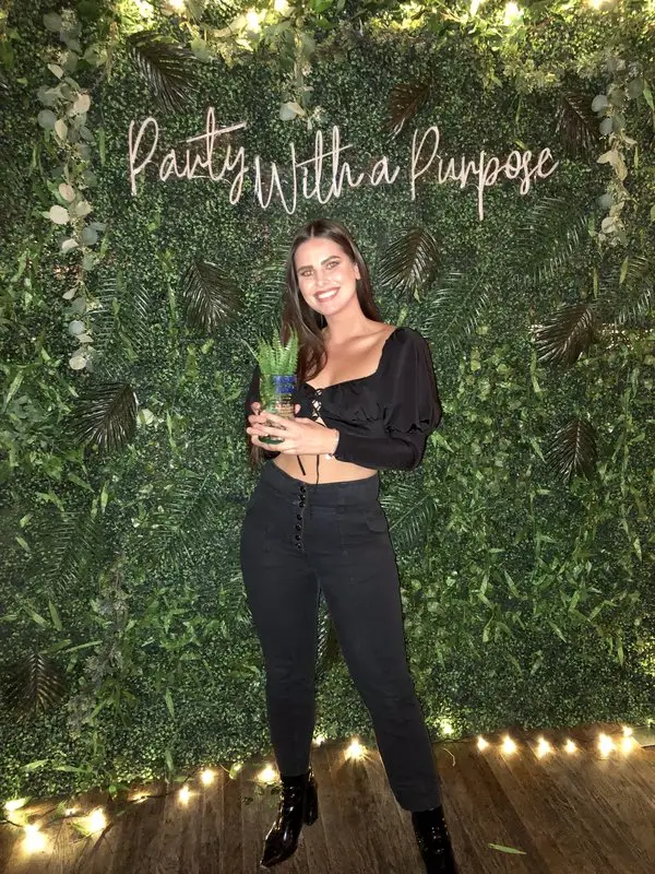 Younger woman holding a plant for a photo op.